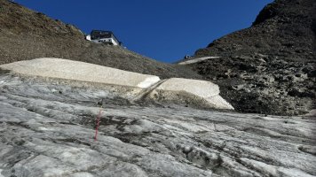 Pohled na horní stanici lanovky Schaufeljochbahn, tyčka jako značení na ledovci pod lanovkou.